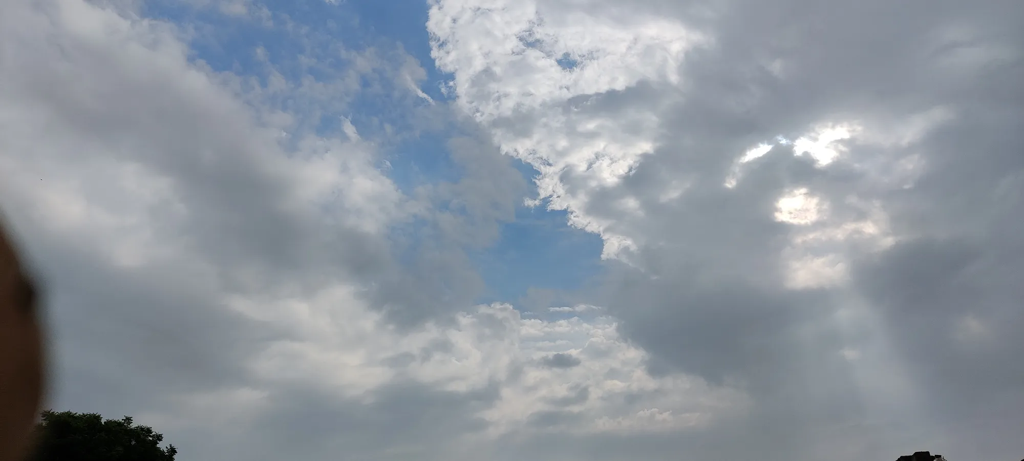 Expansive cloudy sky with sun peeking through